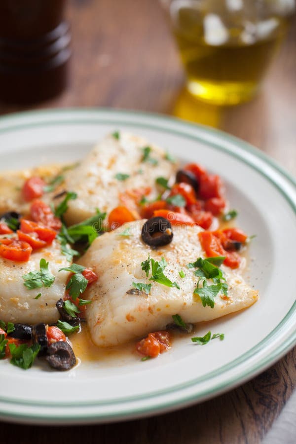 Fish fillet with cherry tomatoes and olives stock photos