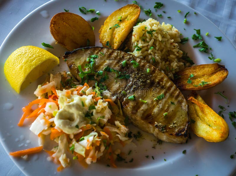 Fish with a Garnish of Fried Potatoes, Rice and Salad Stock Photo Image of greece, fish 82486836