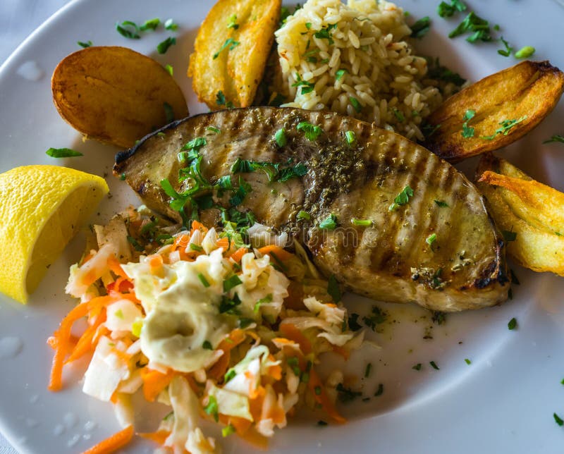 Fish with a Garnish of Fried Potatoes, Rice and Salad Stock Photo Image of food, dark 82496070