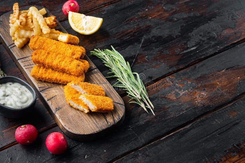 Fish Sticks with vegetables, on wooden cutting board, on old dark wooden table background , with copyspace and space for text stock photography