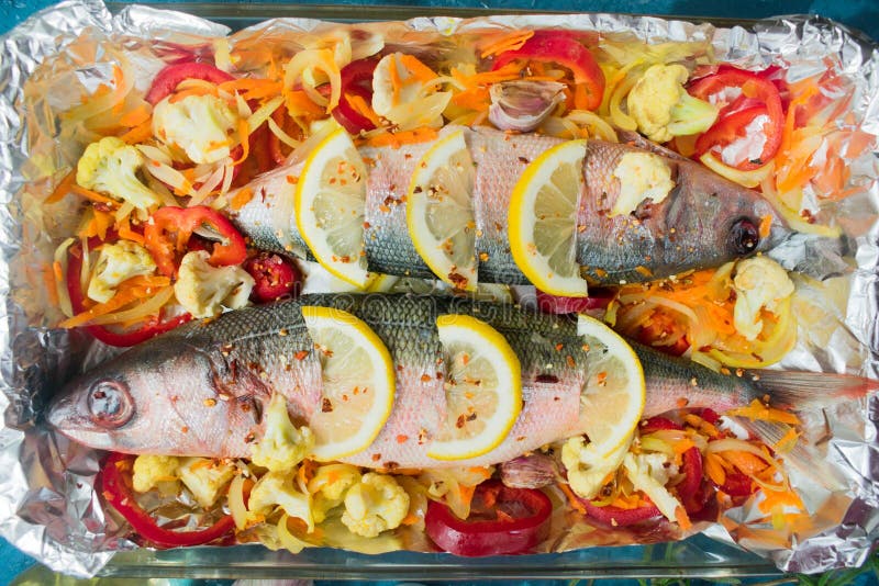 Fish with vegetables and lemon, tomatoes and spices prepared for baking in a bacon. Top view. Close-up. stock image Fish with vegetables and lemon, tomatoes and spices prepared for baking in a bacon. Top view. Close-up. stock image