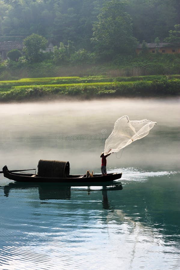 A fisherman casting his net from the boat on the river. A fisherman casting his net from the boat on the river