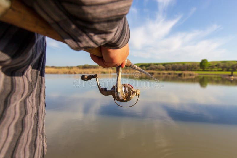 Fisherman catches fish on the shore of the pond stock photo Fisherman catches fish on the shore of the pond stock photo