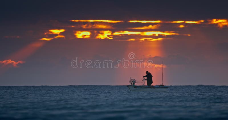 Fisherman and old wooden fishing boat silhouettes against beautiful sea horizon at sunrise dramatic landscape with sun rays