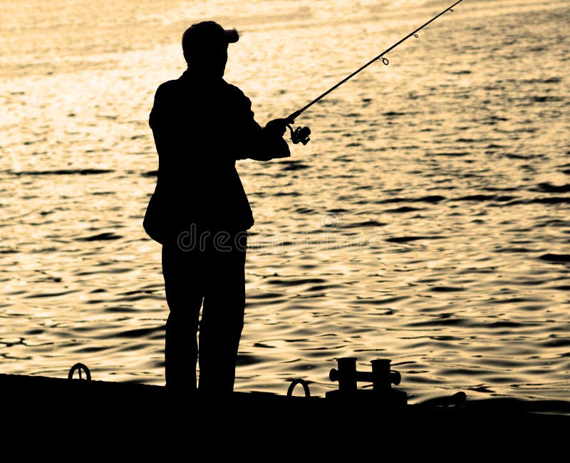 Fisherman standing on edge of dock with fishing rod near river in city