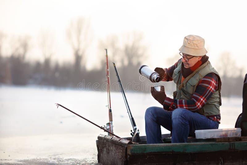 Fisherman taking hot tea while fishing fish stock images Fisherman taking hot tea while fishing fish stock images