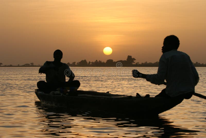 Rybář přejezd jezera při západu slunce v Africe.