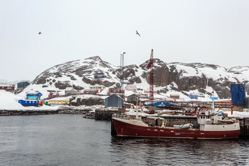 Fishing boat at the pier of Maniitsoq village with colorful houses on the rocks in background, Greenland stock images Fishing boat at the pier of Maniitsoq village with colorful houses on the rocks in background, Greenland stock images