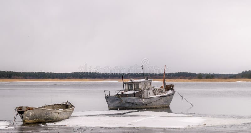 A fishing boat and a rowing boat in a frozen lake or sea.