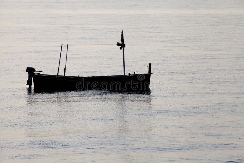 Fishing boat silhouette moored offshore empty, no people around