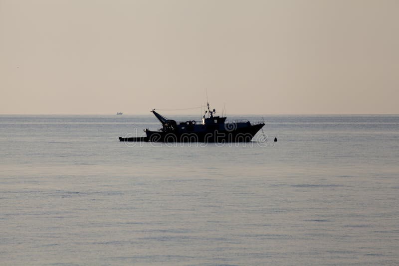 Fishing boat moored silhouette offshore daylight no people around. Fishing boat moored silhouette offshore daylight no people around
