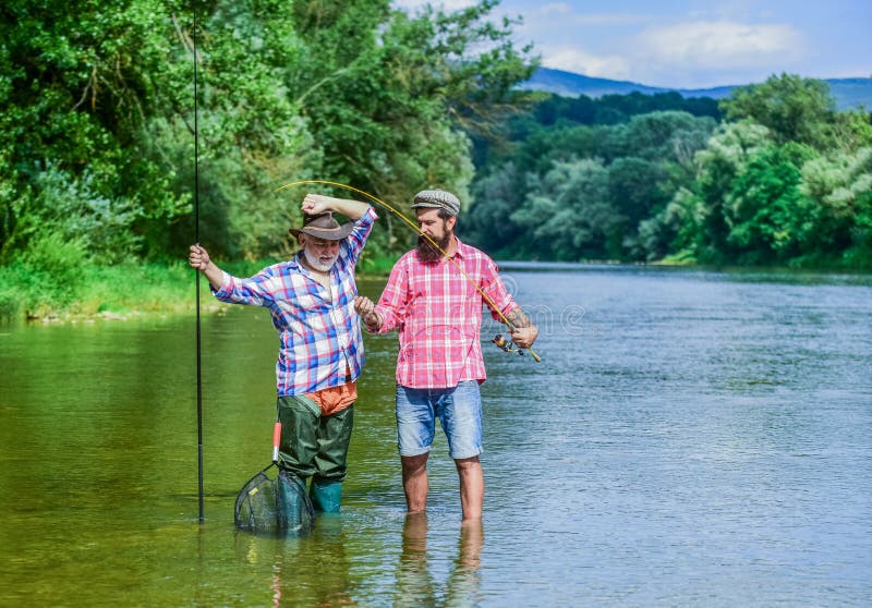 Fishing freshwater lake pond river. Mature man with friend fishing. Summer vacation. Happy cheerful people. Fisherman stock photos Fishing freshwater lake pond river. Mature man with friend fishing. Summer vacation. Happy cheerful people. Fisherman stock photos