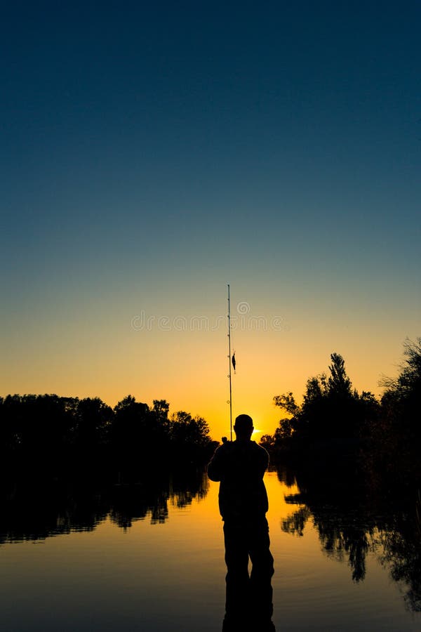 Fishing on the lake at sunset. Silhouette of a fisherman.