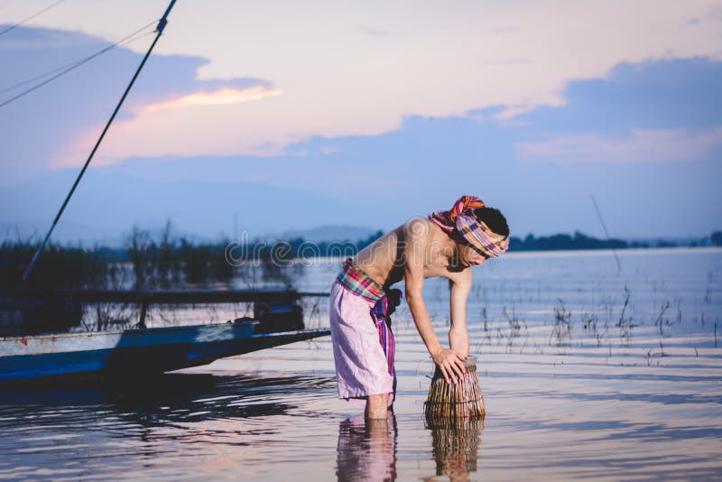 Fishing Man Use Bamboo Fish Trap To Catch Fish in Lake Stock Photo