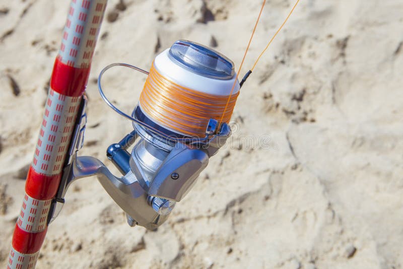 Fishing reel on rod detail with orange showy line for last line