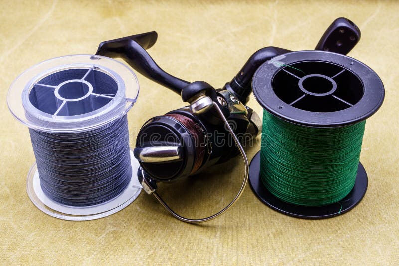 Fishing Reel and Spools of Cords on the Background of Tarpaulin. Green and  Gray Fishing Line Stock Image - Image of line, equipment: 100125295