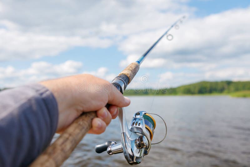 Fishing Rod in a Hand on a Blurred Forest Background. Stock Image