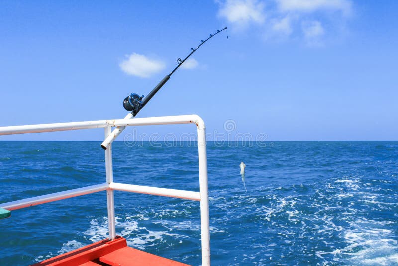 Fishing rod and squid hanging on fishing line are prepared to offshore fishing on the boat in ocean. Fishing rod and squid hanging on fishing line are prepared to offshore fishing on the boat in ocean.