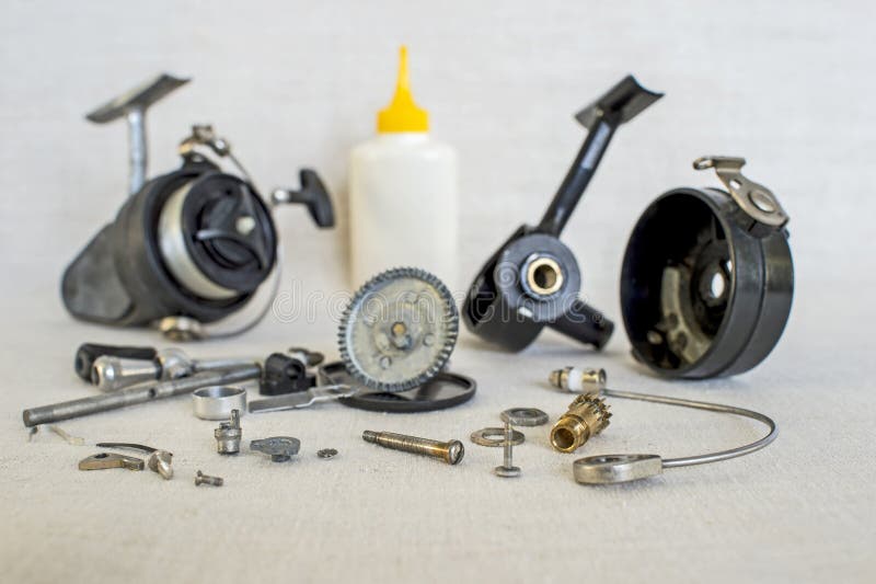 A fishing spinning reel as a whole and a second similar completely disassembled. Concept: parts of a whole.
