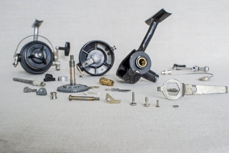 A fishing spinning reel as a whole and a second similar completely disassembled. Concept: parts of a whole.