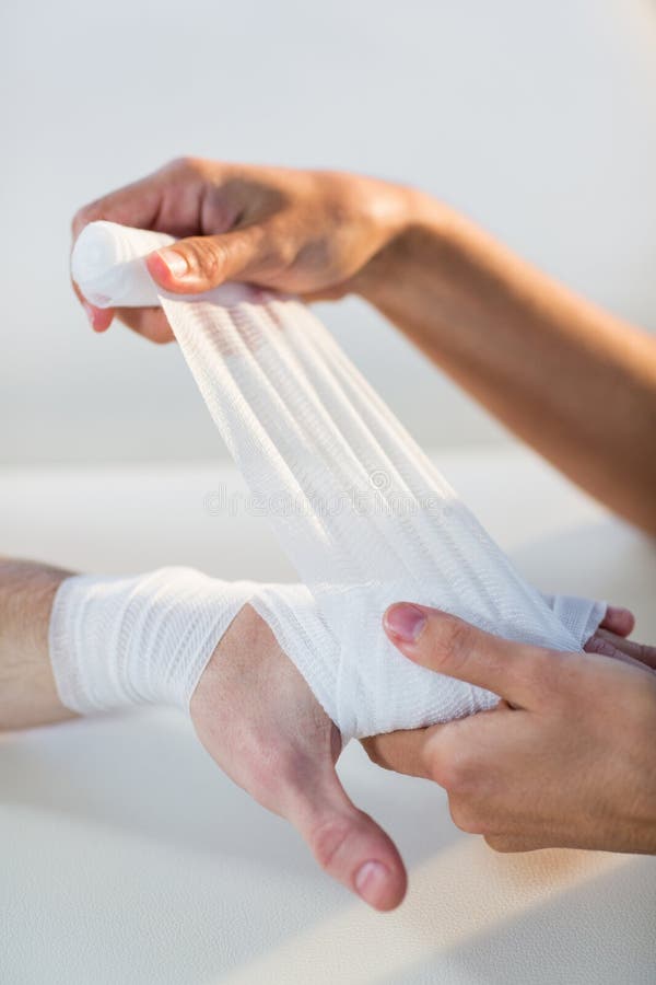 Fisioterapeuta que pone el vendaje en la mano paciente masculina imagen de archivo libre de regalías