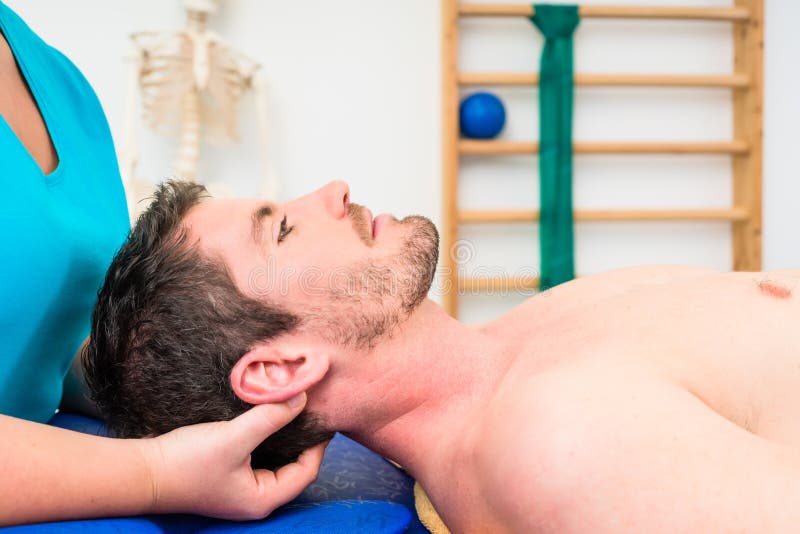 Fisioterapeuta que trata al hombre desnudo-de pecho joven en el sofá imagen de archivo libre de regalías Fisioterapeuta que trata al hombre desnudo-de pecho joven en el sofá imagen de archivo libre de regalías