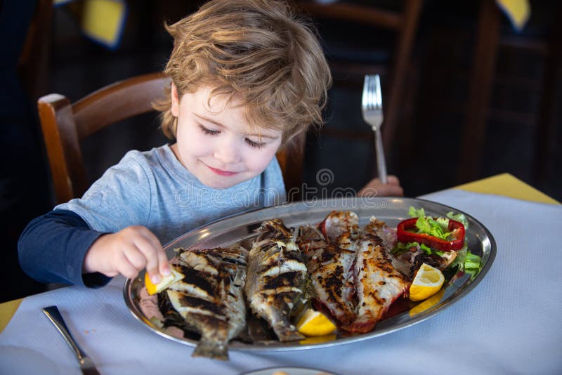 Fish for food. Child wuth lemon and fish plate meal. Dinner in sea restaurant. Seafood with iodine for a healthy diet eating. Fish for food. Child wuth lemon and fish plate meal. Dinner in sea restaurant. Seafood with iodine for a healthy diet eating