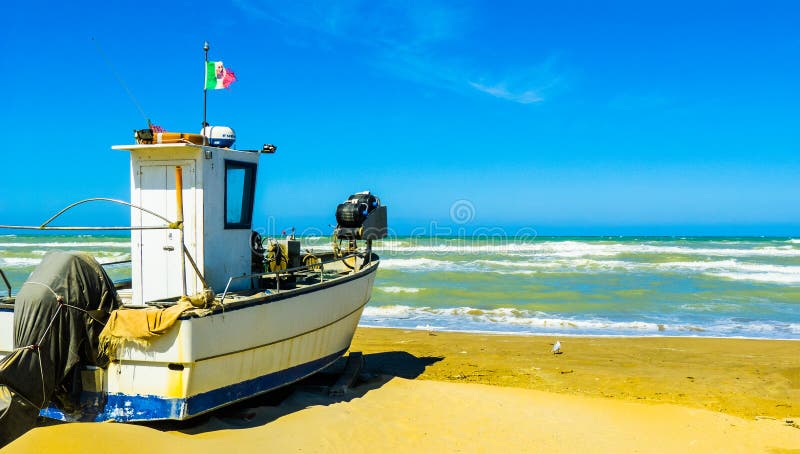 An old fishing boat on the shore of the stormy sea in Pescara, Abruzzo region, Italy â€“ expressive photo without vacationers. An old fishing boat on the shore of the stormy sea in Pescara, Abruzzo region, Italy â€“ expressive photo without vacationers