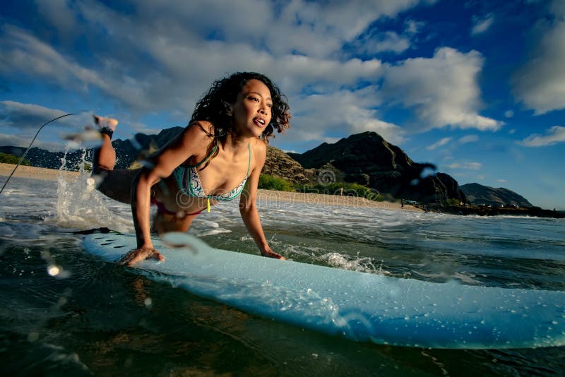 Fit girl having fun starting to surf in ocean water