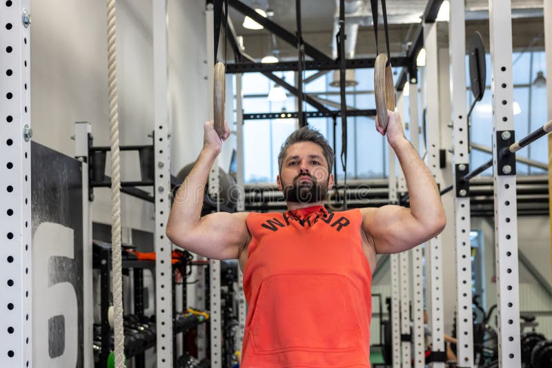 Fit Man Pulling Up on Gymnastic Rings in Gym, Training, Training His