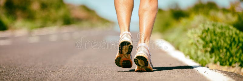 Fit run runner man jogging feet closeup running shoes banner panorama. Athletes legs walking on street for marathon