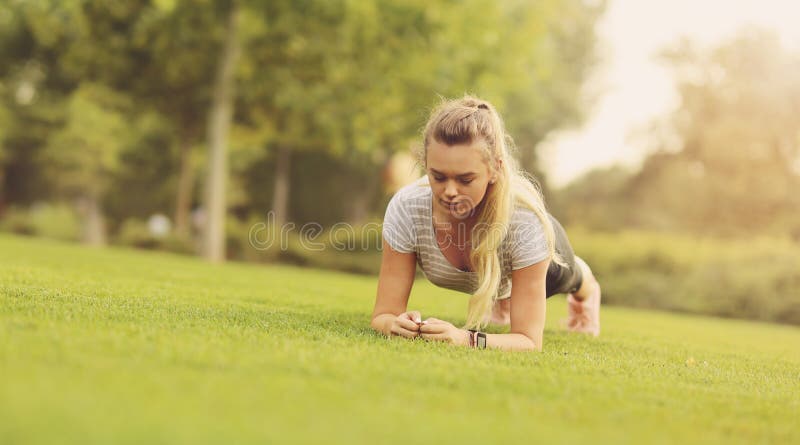 Fit woman doing plank exercise outdoor in the park on the green grass in the morning - Healthy lifestyle, Endurance and motivation stock photography Fit woman doing plank exercise outdoor in the park on the green grass in the morning - Healthy lifestyle, Endurance and motivation stock photography