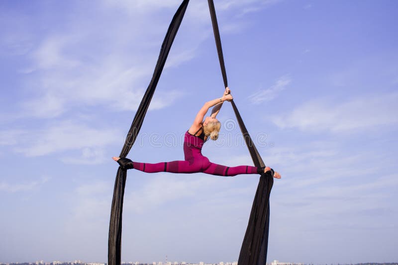 Fit woman in skinny skinny clothes dancing with aerial silk on a sky background, gymnast training on aerial silk. Fit woman in skinny skinny clothes dancing with aerial silk on a sky background, gymnast training on aerial silk