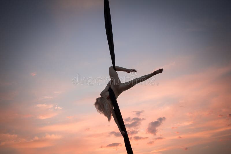 Fit woman in skinny skinny clothes dancing with aerial silk on a sky background, gymnast training on aerial silk. Fit woman in skinny skinny clothes dancing with aerial silk on a sky background, gymnast training on aerial silk