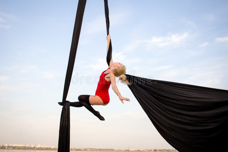 Fit woman in skinny skinny clothes dancing with aerial silk on a sky background, gymnast training on aerial silk. Fit woman in skinny skinny clothes dancing with aerial silk on a sky background, gymnast training on aerial silk