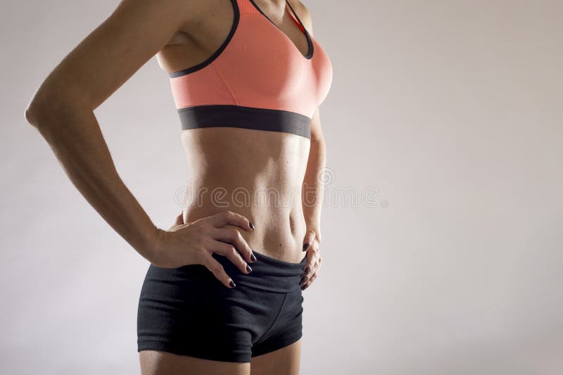 Cropped shot of a young slim woman with toned stomach demonstrating her abs  isolated on a white background. Result of fitness, diet, healthy lifestyle.  Female belly after a workout Stock Photo