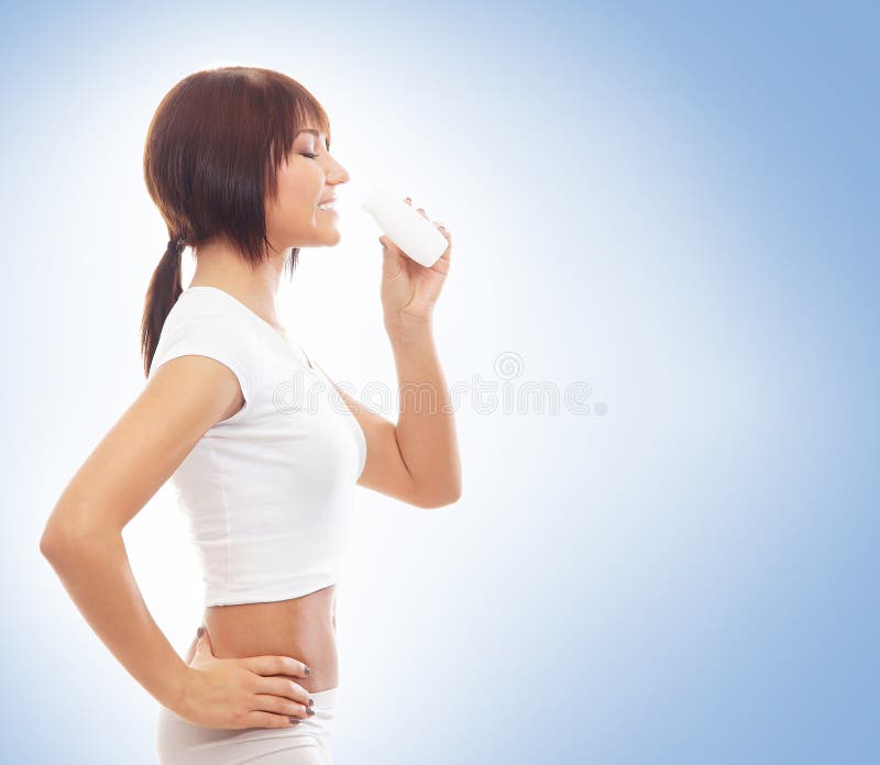 A fit woman in white sporty clothes drinking water