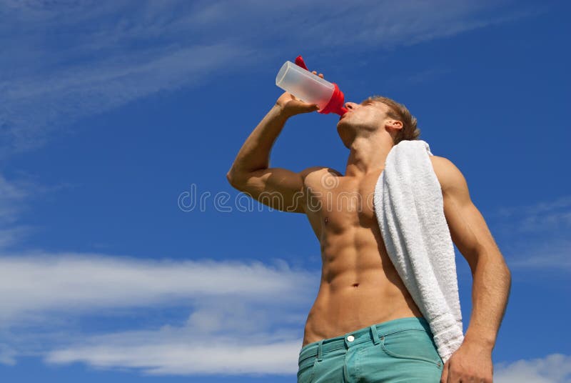 Fit young man with white towel over his shoulder, drinking water. Fit young man with white towel over his shoulder, drinking water.