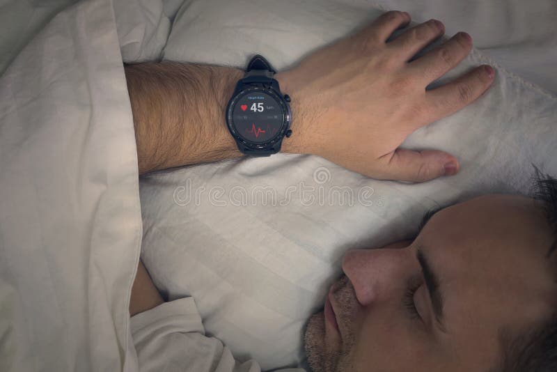 a man sleeps on a bed with a heart rate check in his sleep. Smart watches measure the pulse on the hand of a