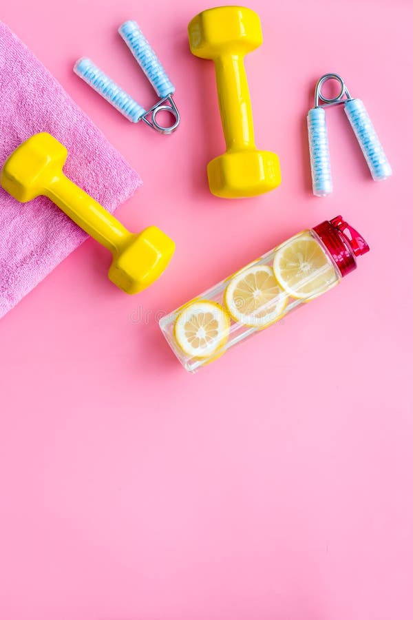Foto de Fitness background. Equipment for gym and home. Jump rope,  dumbbells, expander, water on pastel pink background top view copy space do  Stock