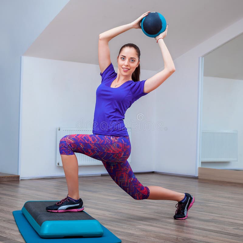 Fitness girl, wearing in sneakers posing on step board with ball