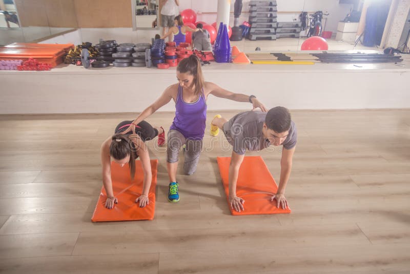 Fitness instructor training correcting push up group three peop royalty free stock images