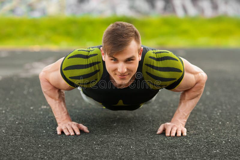 Fitness man doing push-ups in the stadium, cross training workout. Sporty male training outside stock photos Fitness man doing push-ups in the stadium, cross training workout. Sporty male training outside stock photos