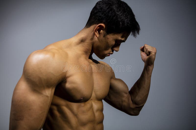 A fitness model flexes his bicep looking towards the muscle. Medium close up. A fitness model flexes his bicep looking towards the muscle. Medium close up.