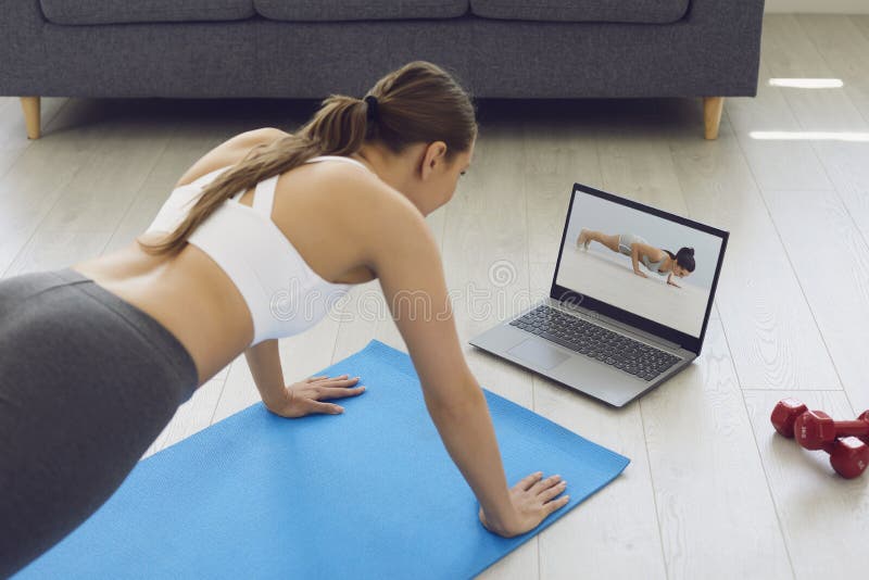 Fitness online. jong , geschikt meisje thuis op de vloer , oefeningen die opwarmen en een video fitness - les gebruiken