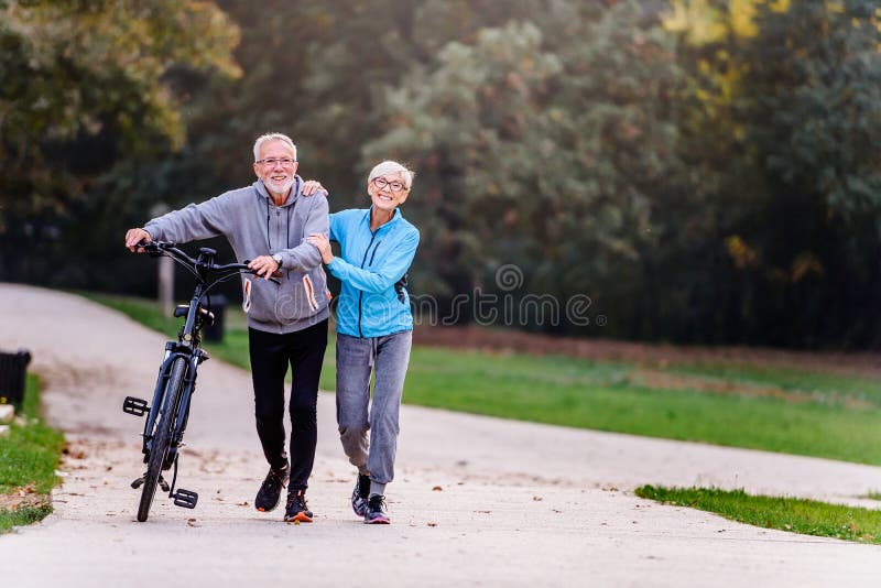 Fitness routines for elderly people. Working out together. Exercise to stop aging. Cheerful active senior couple walking in the park. Fitness routines for elderly people. Working out together. Exercise to stop aging. Cheerful active senior couple walking in the park