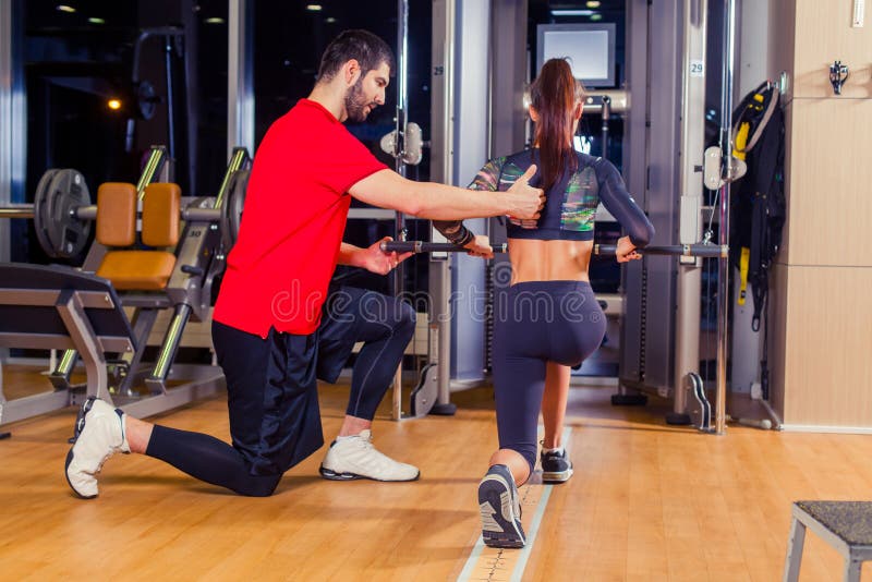 Fitness, sport, opleiding en mensenconcept - Persoonlijke trainer die vrouw het werken met in gymnastiek bevorderen royalty-vrije stock afbeelding Fitness, sport, opleiding en mensenconcept - Persoonlijke trainer die vrouw het werken met in gymnastiek bevorderen royalty-vrije stock afbeelding