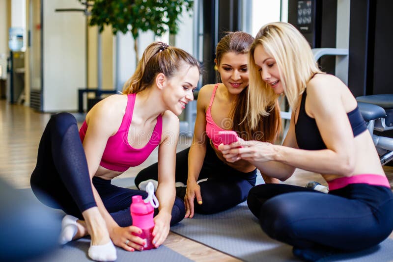 Fitness, sport, training, gym and lifestyle concept - group of happy women with bottles and smartphone in gym. royalty free stock photos Fitness, sport, training, gym and lifestyle concept - group of happy women with bottles and smartphone in gym. royalty free stock photos