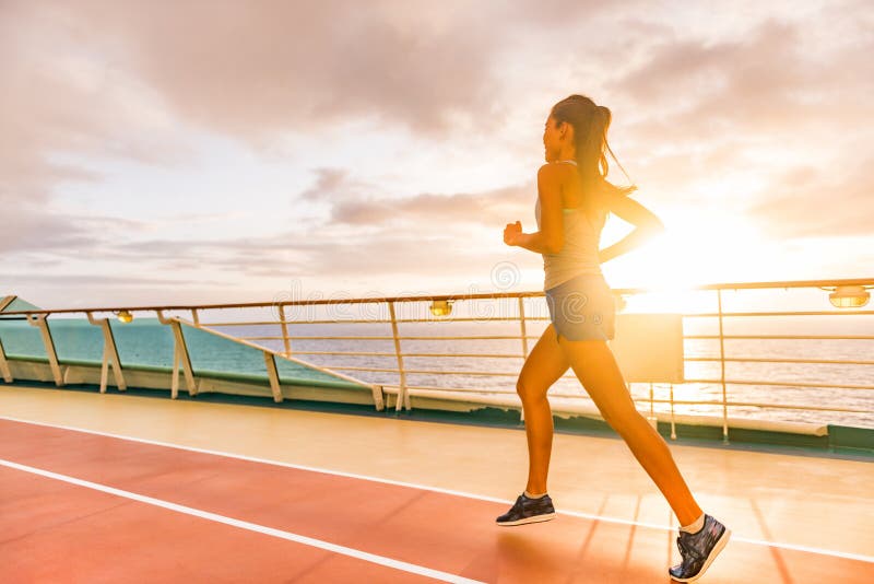 Fitness-tjej som kör en kardioträning på kryssningssemester Anpassa kvinnan att jogga vid solnedgång på körbanor på kryssningsfar