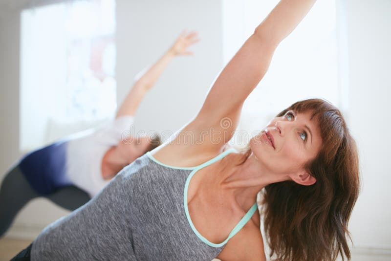 Portrait of mature women practicing yoga at gym. Fitness female doing Triangle yoga Pose, Trikonasana. Portrait of mature women practicing yoga at gym. Fitness female doing Triangle yoga Pose, Trikonasana.